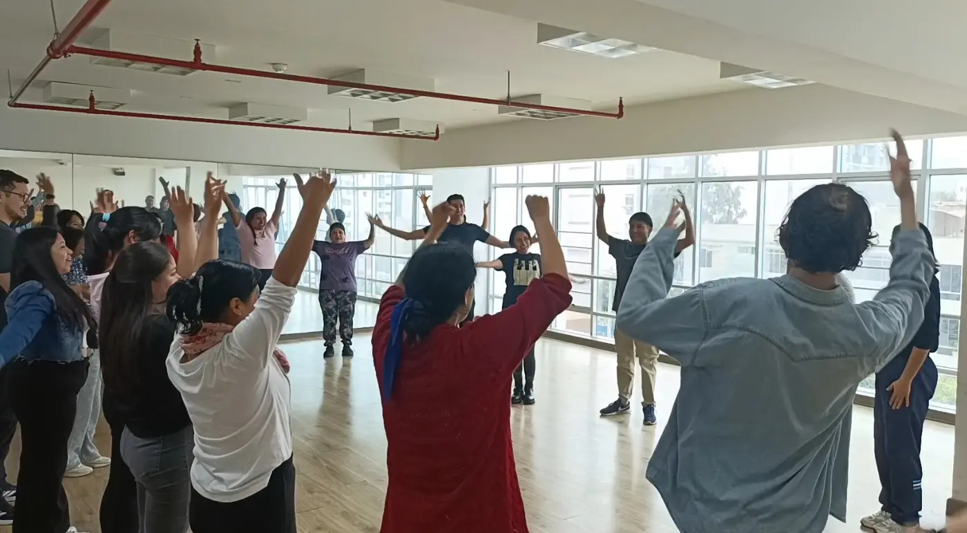 Participantes de un taller de improvisación con los brazos en alto